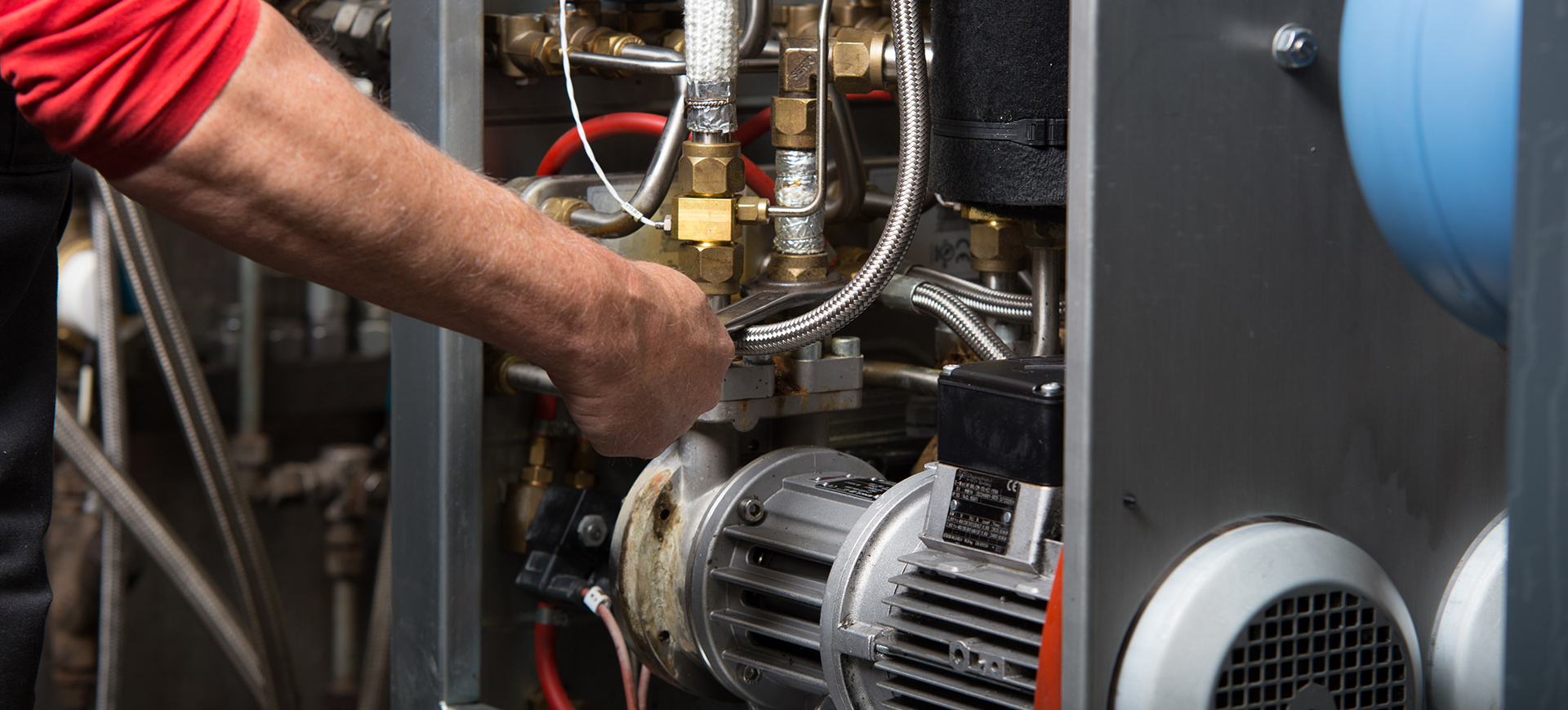 Ein Handwerker mit einem Schraubenschlüssel repariert ein komplexes System aus Rohren und Ventilen