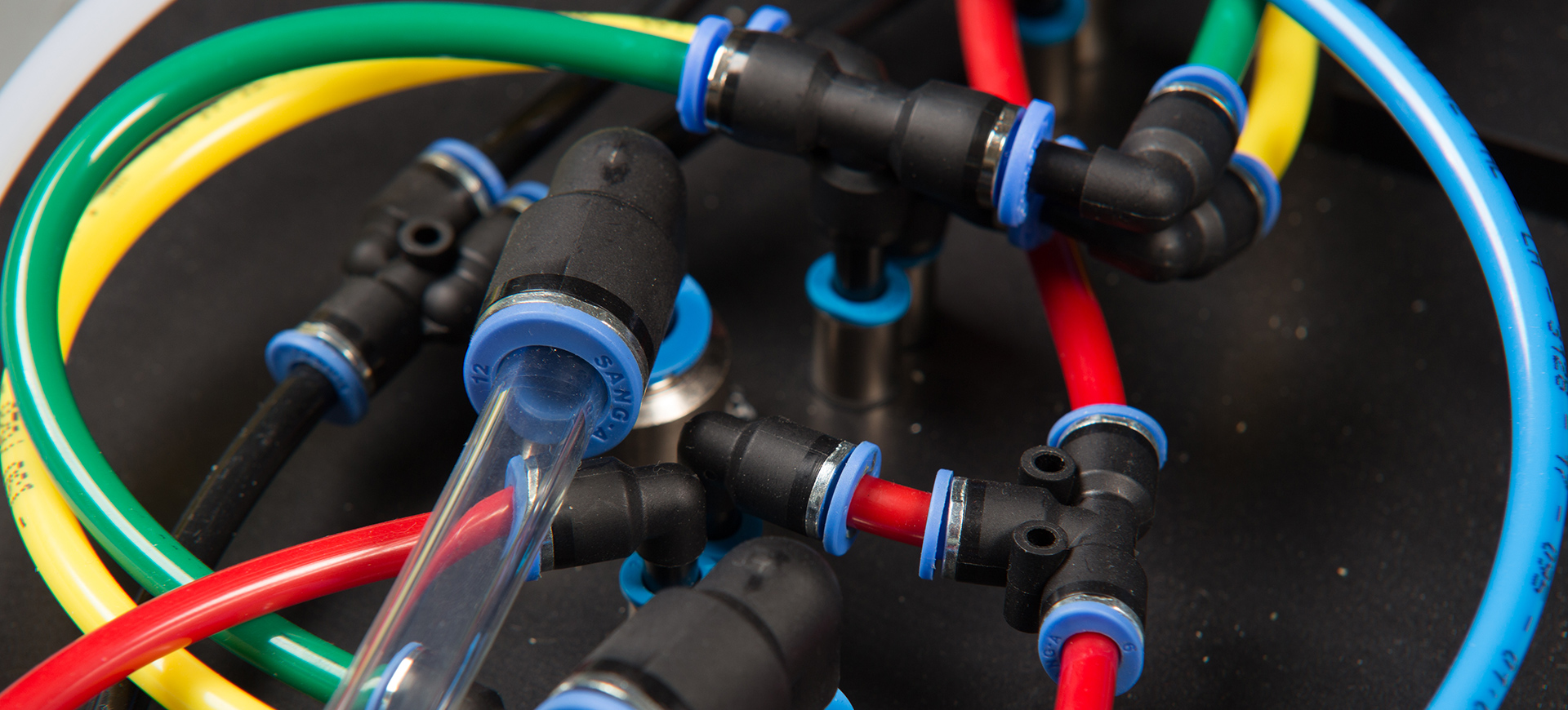 Nahaufnahme einer pneumatischen Verrohrung mit roten, gelben, grünen und blauen Schläuchen
